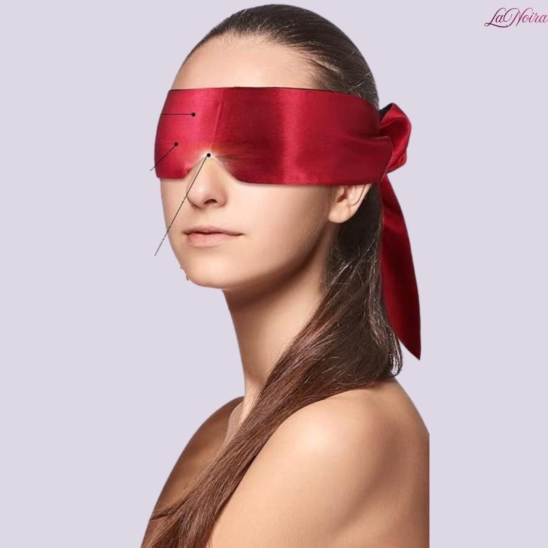 Woman wearing red satin blindfold with tied ribbon, shown in side profile against light background