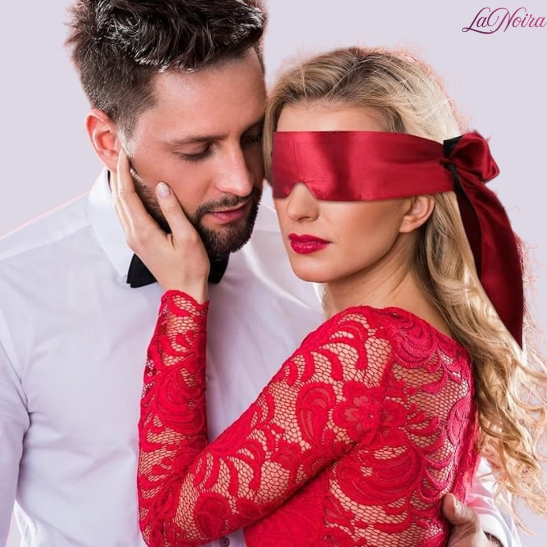 Couple in red-themed attire with woman wearing satin blindfold, styled for romantic roleplay mood