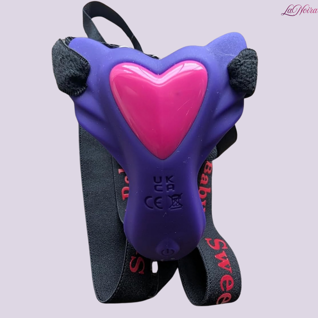 Close-up of purple Sweet Baby wearable vibrator with pink heart detail and adjustable elastic straps