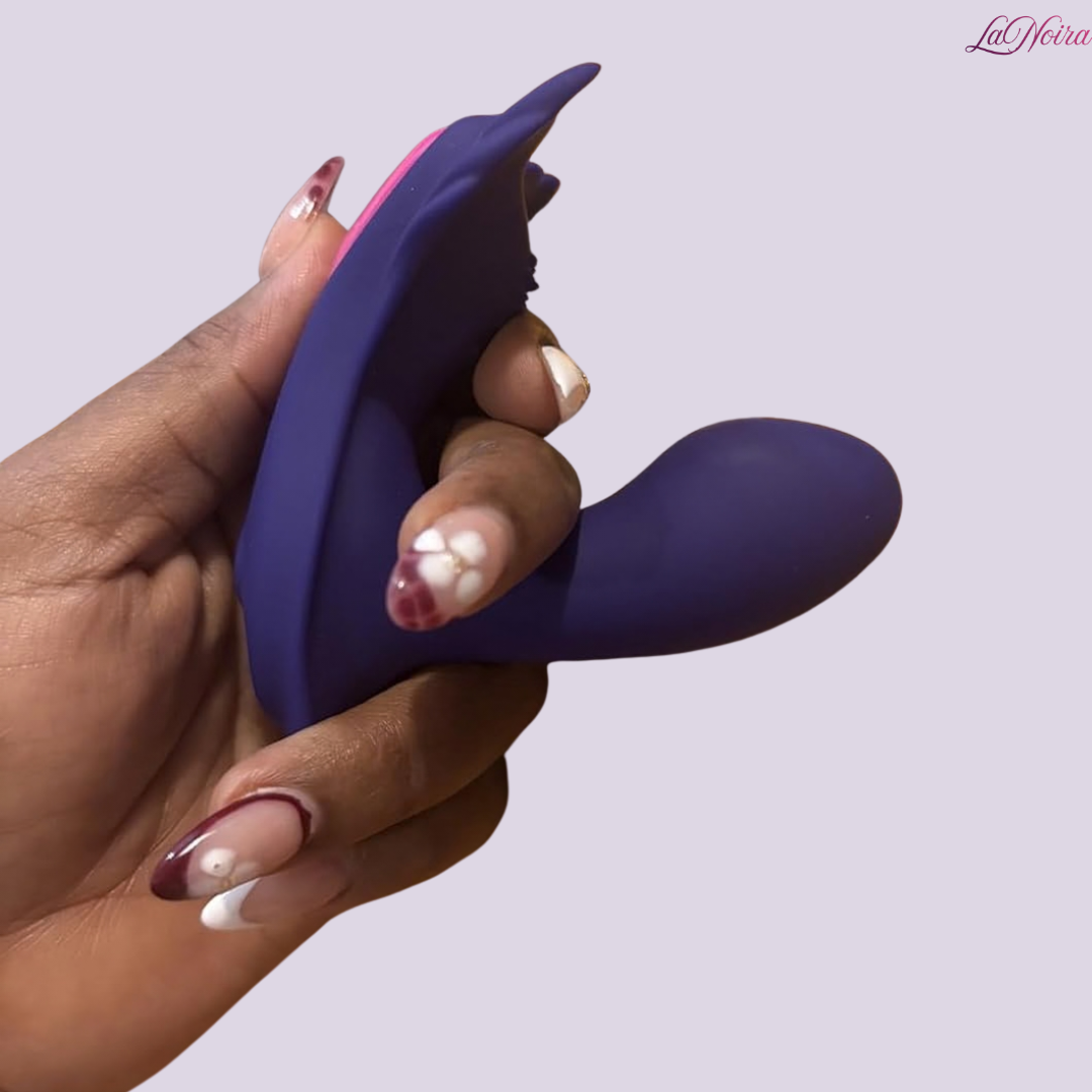 Hand holding purple silicone wearable vibrator showing curved internal arm and flexible body design