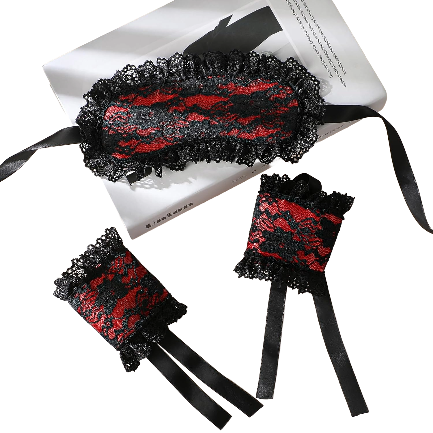 Lace blindfold and cuffs set placed on book with decorative floral lace detailing and ribbon straps