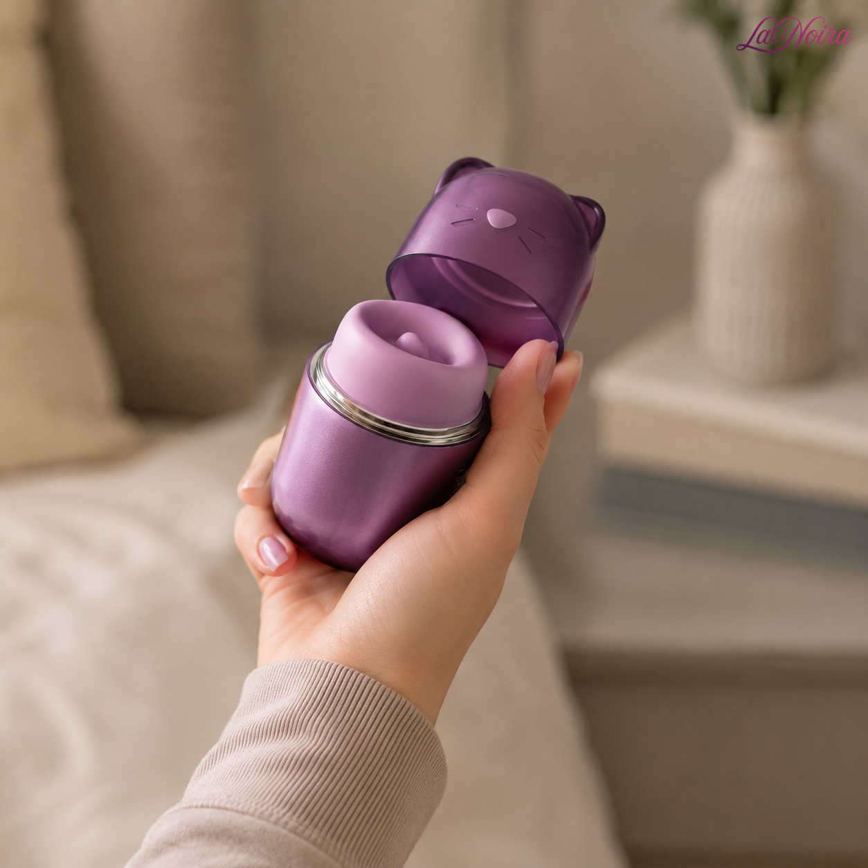 Hand holding the SVAKOM Klitty triple-action clitoral suction and licking massager with protective cat-shaped cap removed to reveal the stimulation head – LaNoira India